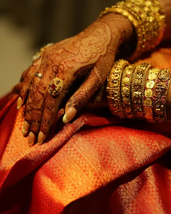 Hands with bridal mehendi and gold bangles